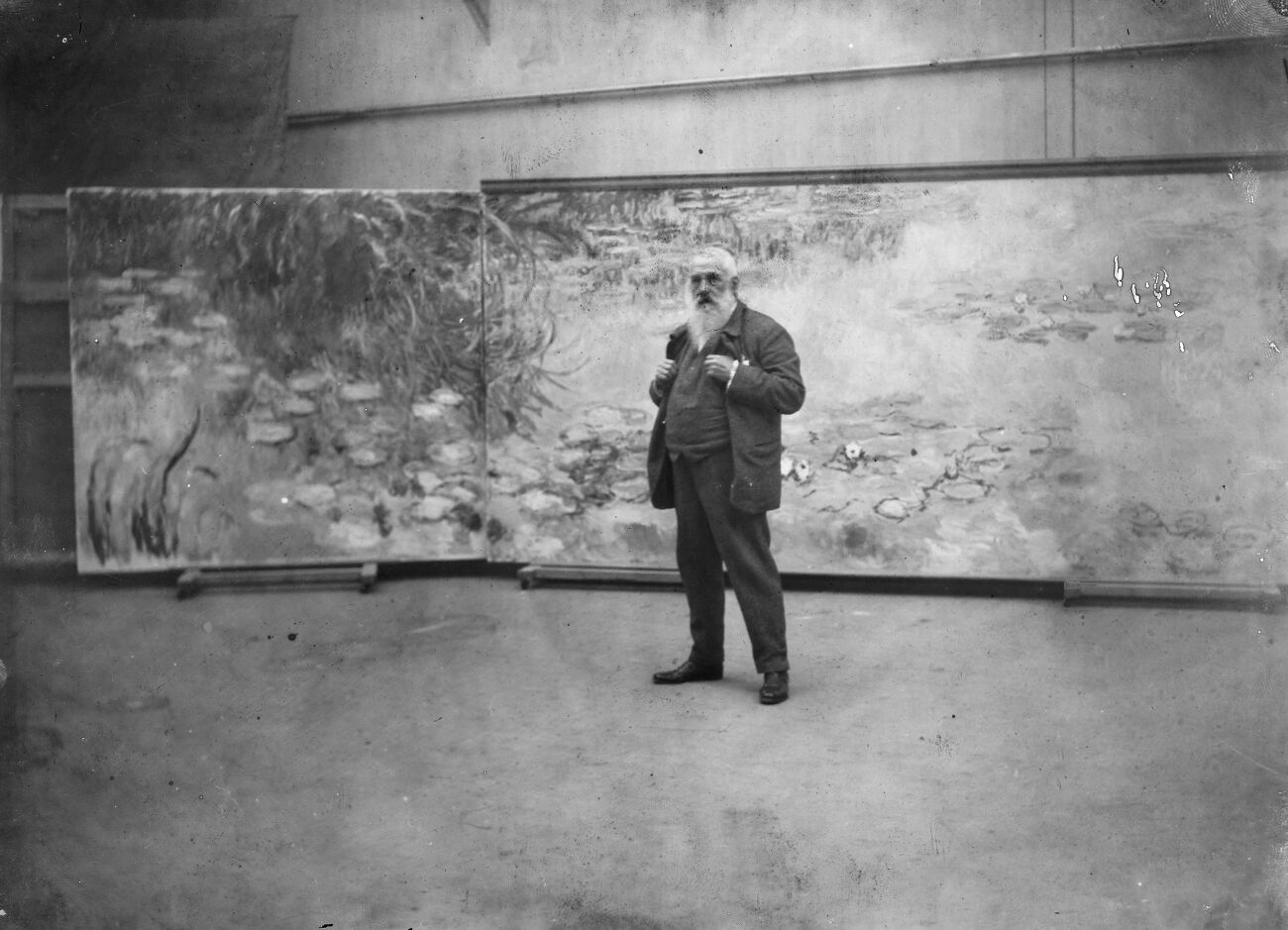 Claude Monet (1840-1926), peintre français, devant les "Nymphéas" dans l'atelier de sa propriété de Giverny (Eure). Vers 1915-1920