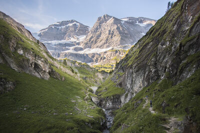 Deux randonneurs s'engouffre dans une vallée surplombée d'un glacier suisse